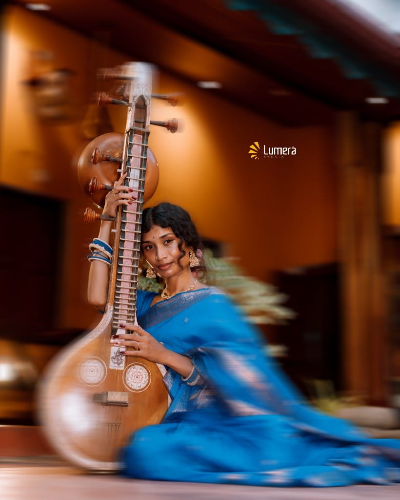 Woman in a blue saree posing with a veena during a Tamil cultural themed 21st birthday portrait session at Tamil Natchaar House in Jaffna, photographed by Lumera Studio.